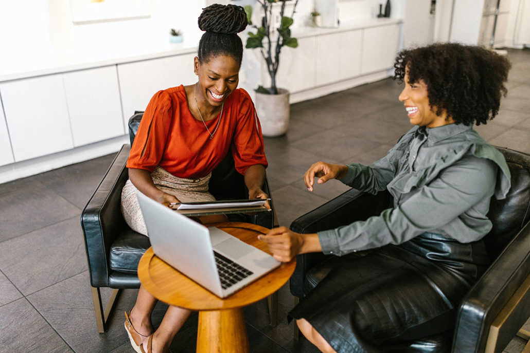 Two professional women laughing and enjoying their work.